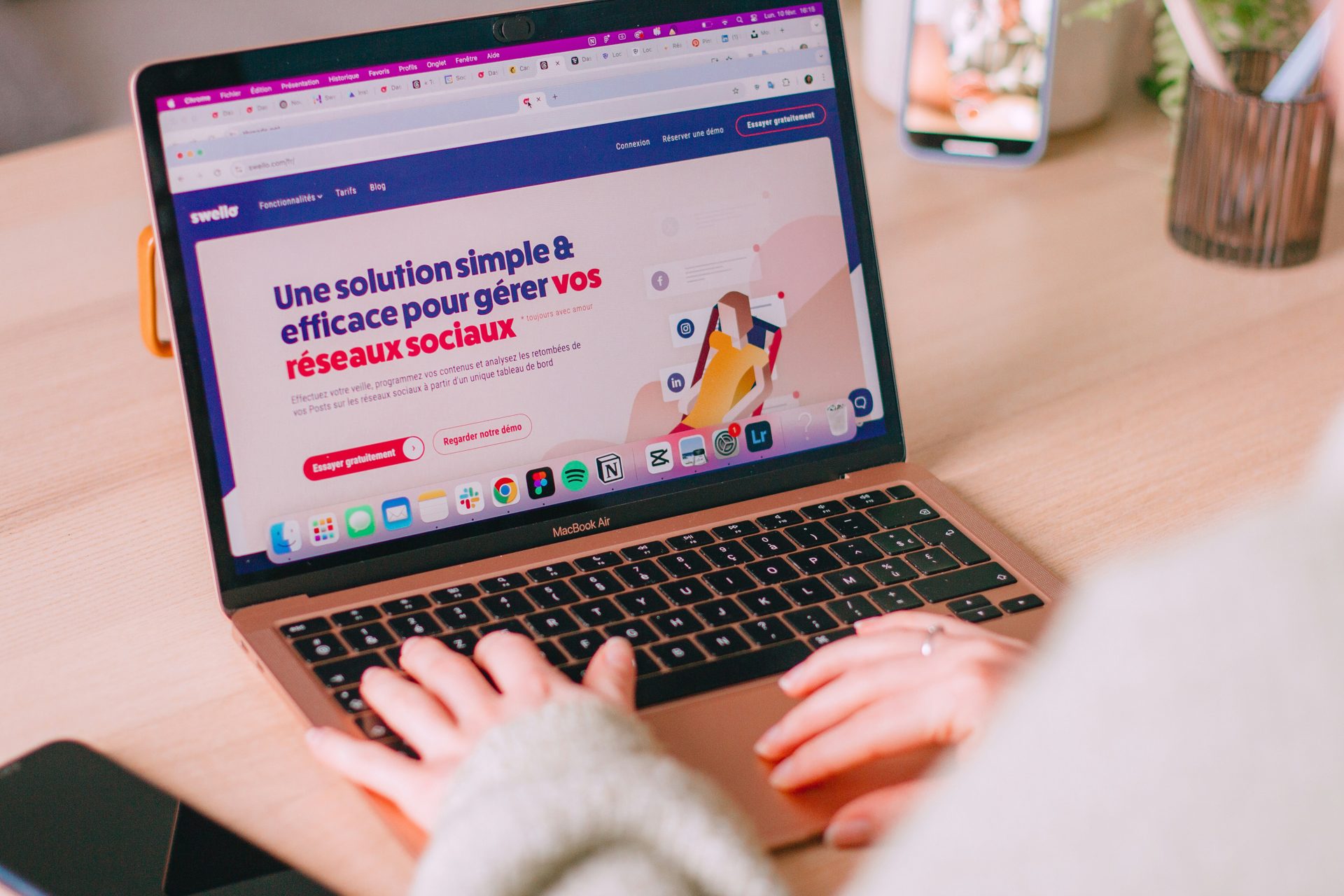 Personne qui tape sur un ordinateur portable posé sur un bureau en bois
